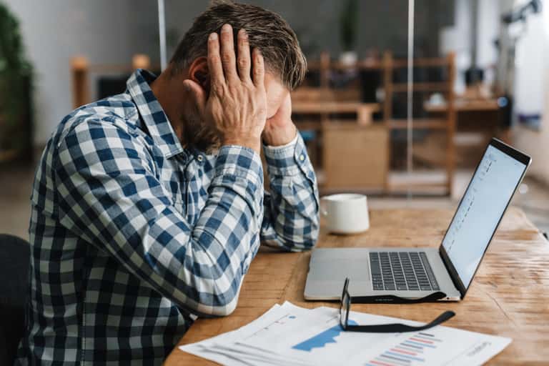 Unhappy man with headache working with a laptop.